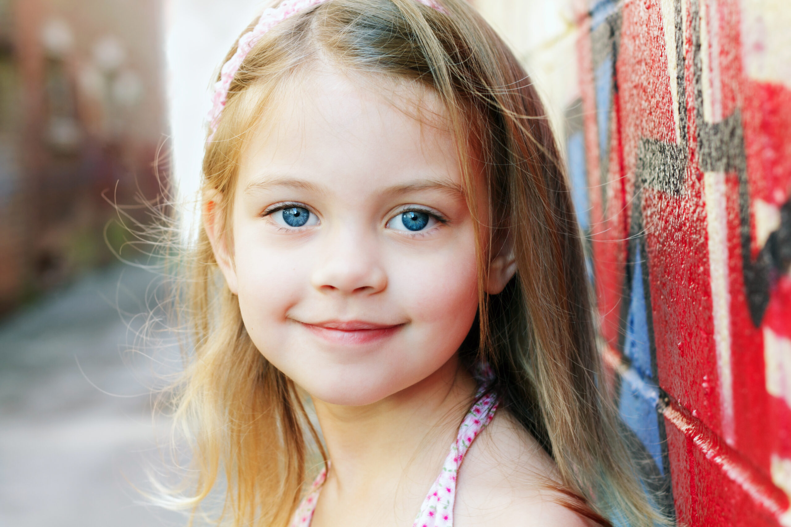 Little,Girl,In,An,Urban,Setting,Smiles,At,The,Camera. - Lindsay Sealey